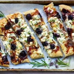 Balsamic cherry feta pizza cut into slices on a tray