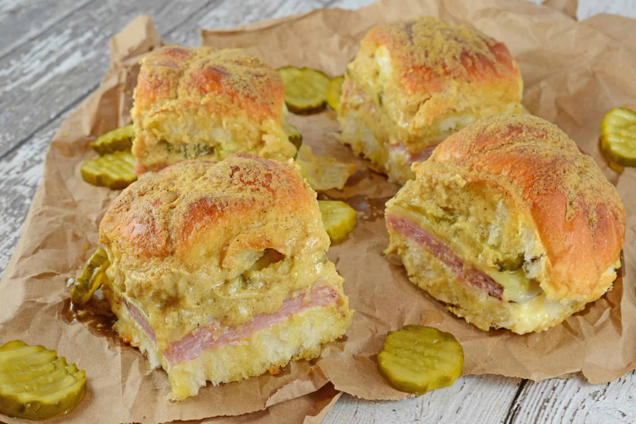 Cuban Sliders are made with layers of ham, pickles, and cheese between delicious sweet Hawaiian rolls. An easy and yummy appetizer! #cubansliders #minicubansandwiches www.savoryexperiments.com