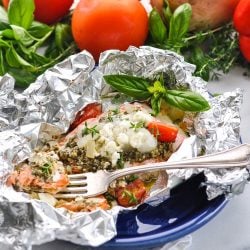 angled shot of Mediterranean salmon in foil pack on plate