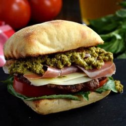 Prosciutto pesto burger on a black surface