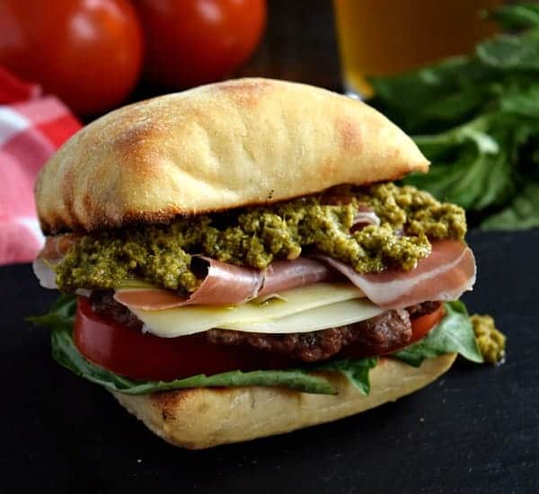 Prosciutto pesto burger on a black surface