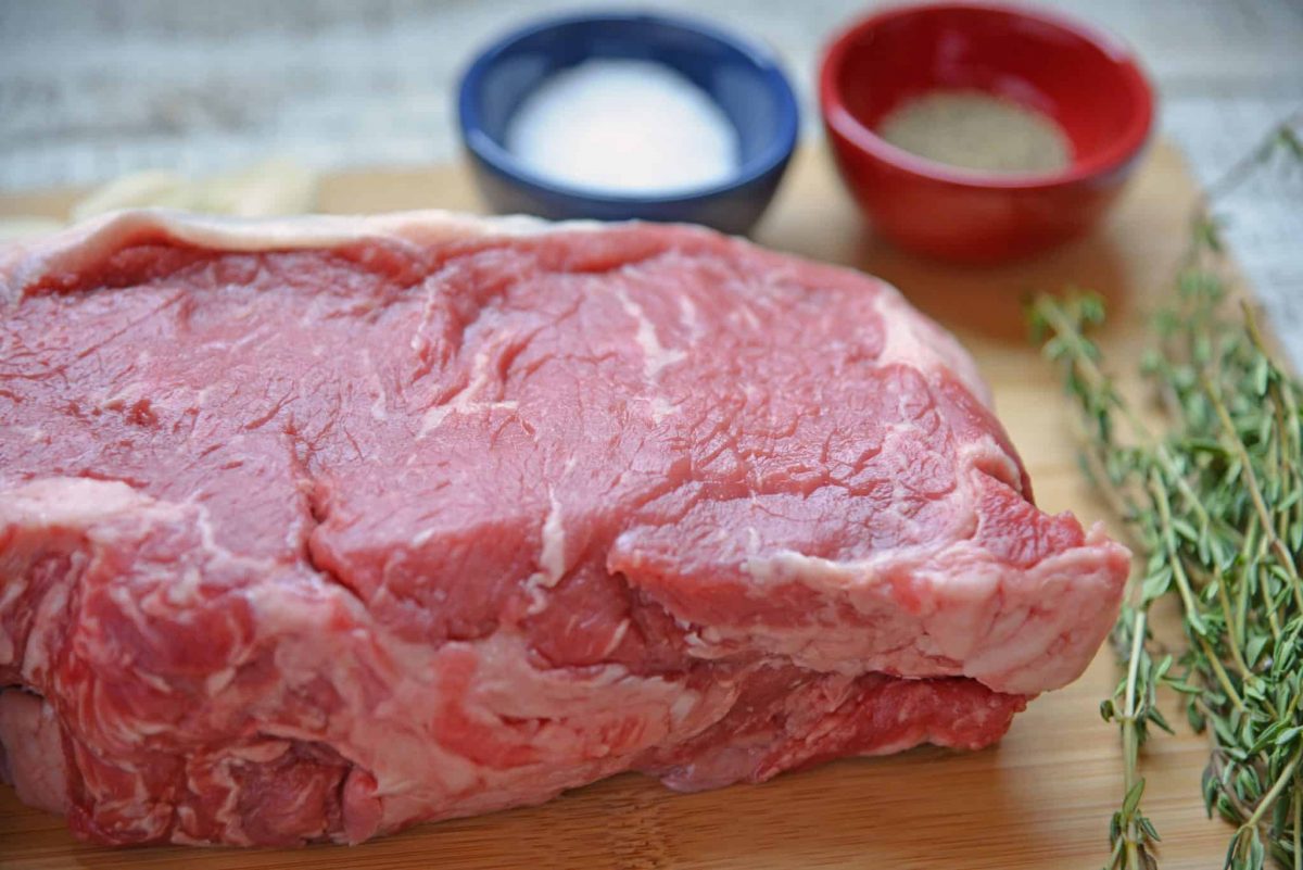 two pieces of New York strip steak on a cutting board