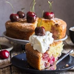 A slice of fresh cherry cake on a black plate