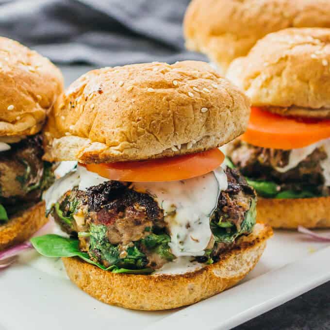 Four greek burger on a white platter