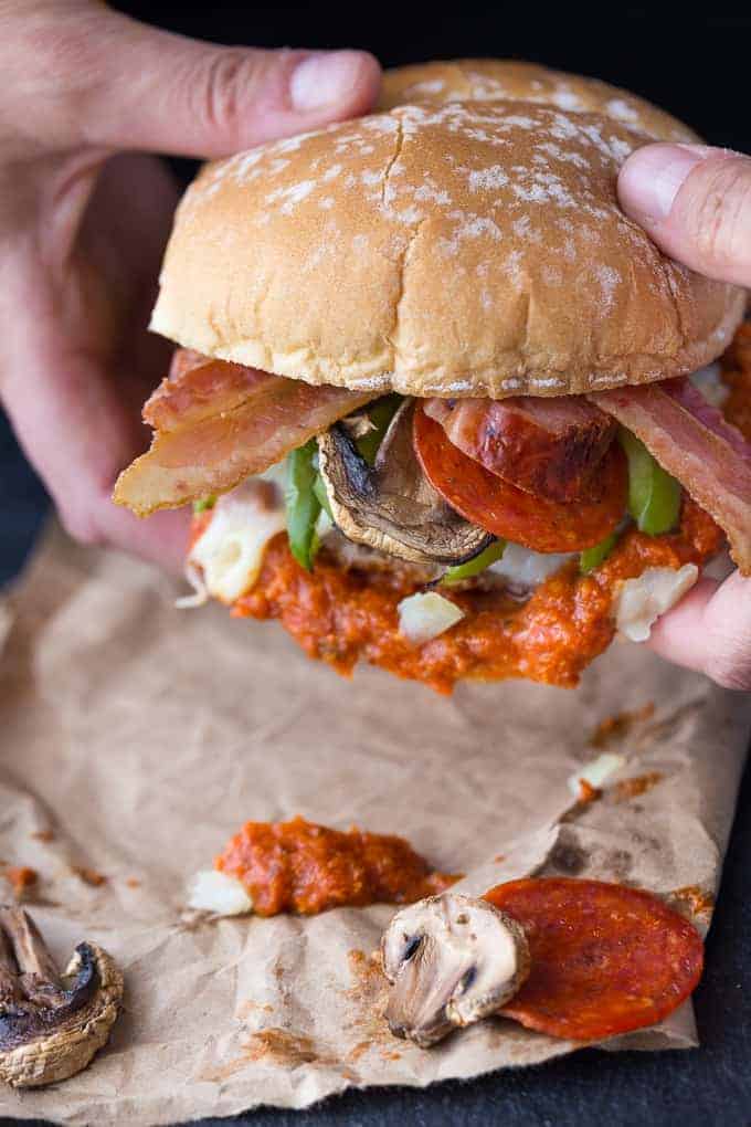 Two hands holding a pizza burger