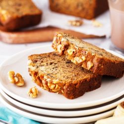 Two slices of pumpkin banana bread on a stack of white plates