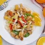 This Orange Chicken Recipe is amped up with bell pepper, baby corn and carrots in a delicious savory orange sauce over rice. Garnish with scallions sesame seeds and orange zest for the best homemade Chinese food. #homemadeorangechicken #orangechickenrecipe www.savoryexperiments.com