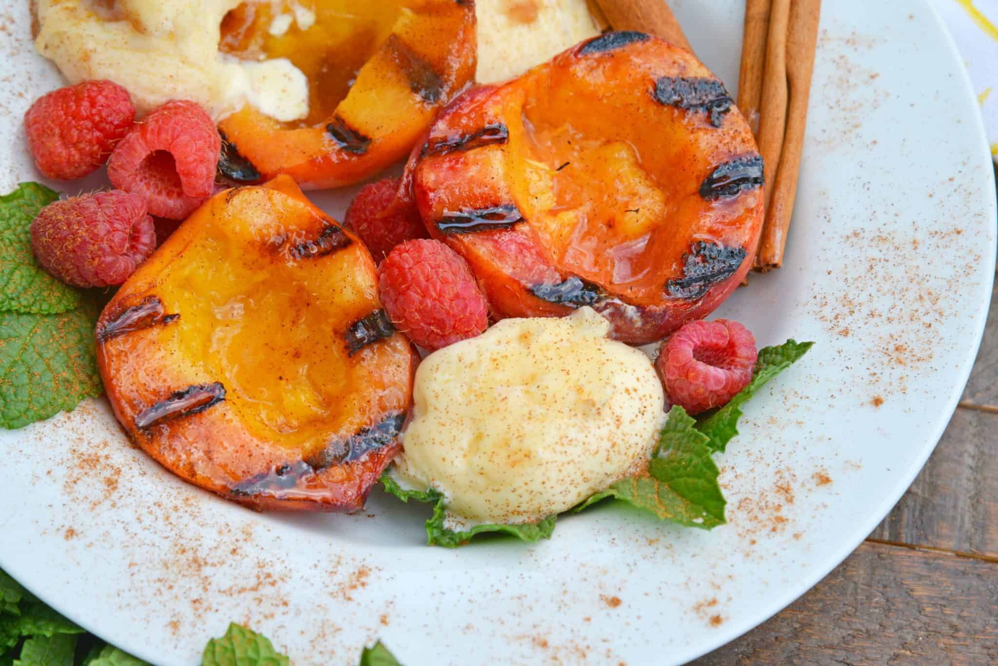 Grilled Peaches basted with cinnamon brown sugar and butter are the ultimate summer dessert idea. Add vanilla ice cream and fresh raspberries for dessert perfection! #grilledpeaches www.savoryexperiments.com