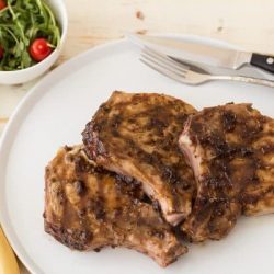 Three jalapeno raspberry pork chops on a white plate