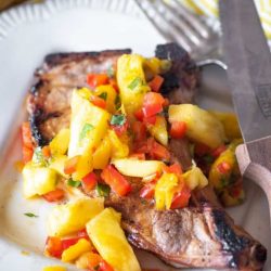 Tropical pork chop on a white plate with a fork and knife