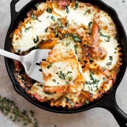 Lasagna in a skillet with a spatula