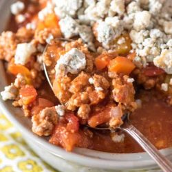 Buffalo chicken chili in a white bowl topped with blue cheese