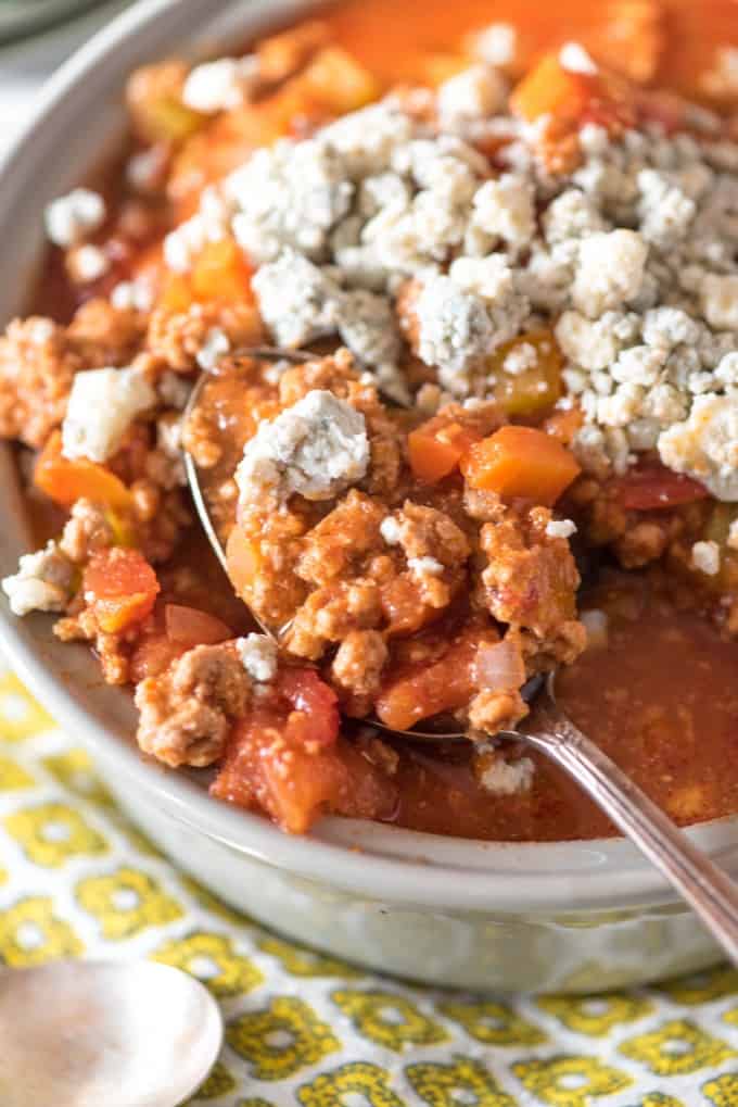 Buffalo chicken chili in a white bowl topped with blue cheese