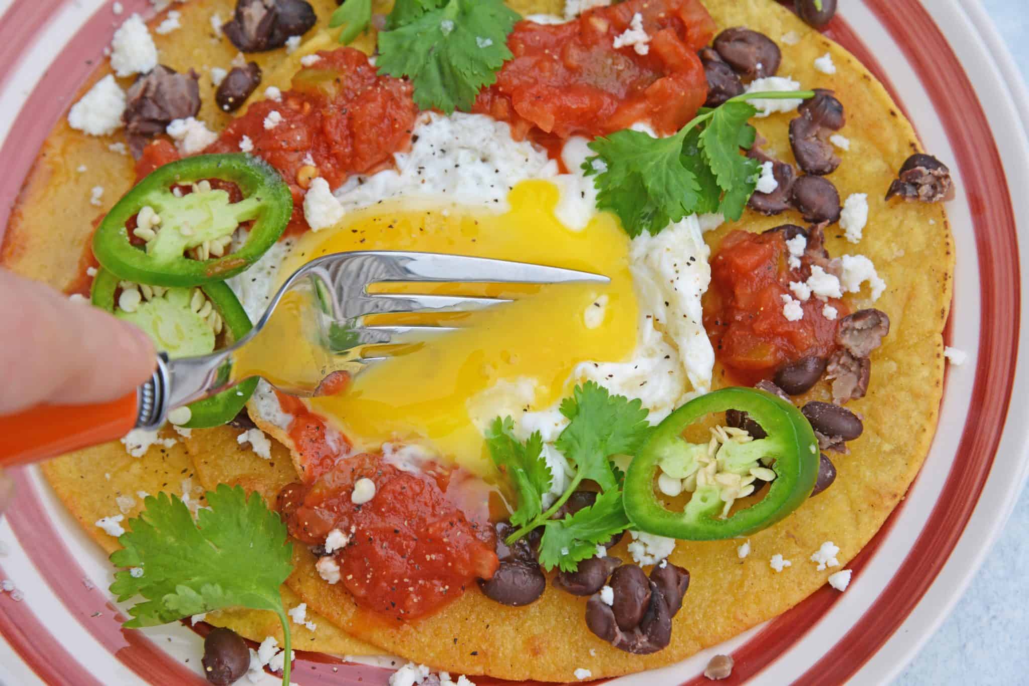 Huevos Rancheros are a great way to spice up your breakfast. Lacey eggs with a runny yolk over warm corn tortillas, chunky salsa, black beans, cilantro and queso fresco. #huevosrancheros www.savoryexperiments.com 