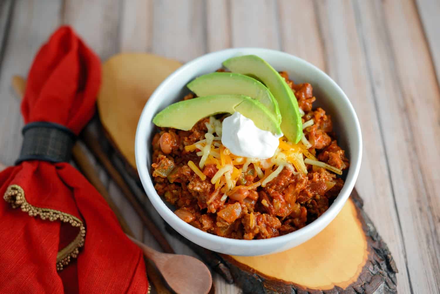 Quick chili in a white bowl topped with sour cream and avocado