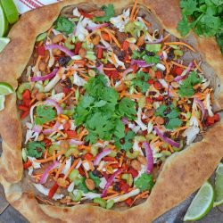 Spicy Thai Chicken Pizza uses a rich peanut satay sauce with shredded chicken, colorful vegetables and topped with sweet honey roasted peanuts and spicy chili oil. #thaichicken #homemadepizza www.savoryexperiments.com