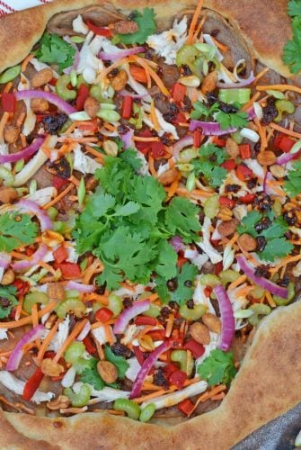 Spicy Thai Chicken Pizza uses a rich peanut satay sauce with shredded chicken, colorful vegetables and topped with sweet honey roasted peanuts and spicy chili oil. #thaichicken #homemadepizza www.savoryexperiments.com