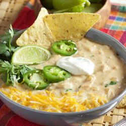 White chicken chili in a blue bowl with tortilla chips