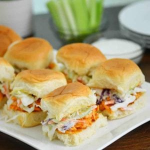 Buffalo chicken sliders on a white plate with celery in the background