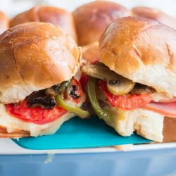 Italian ham turkey and cheese sliders on a blue spatula