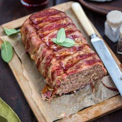Pancetta wrapped meatloaf on a cutting board with a knife