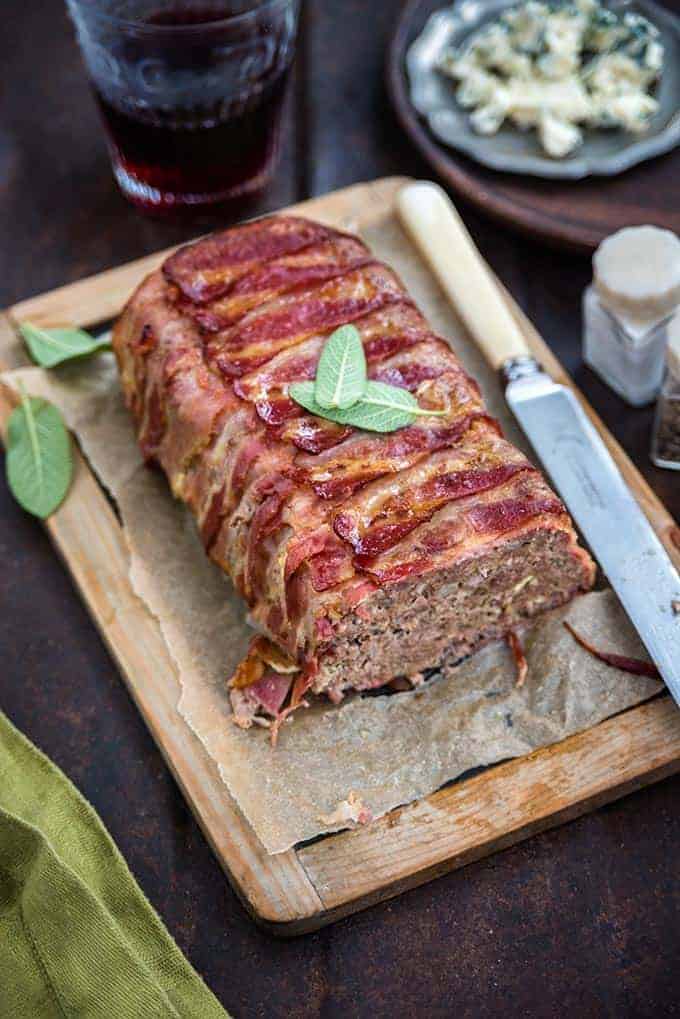 Pancetta wrapped meatloaf on a cutting board with a knife