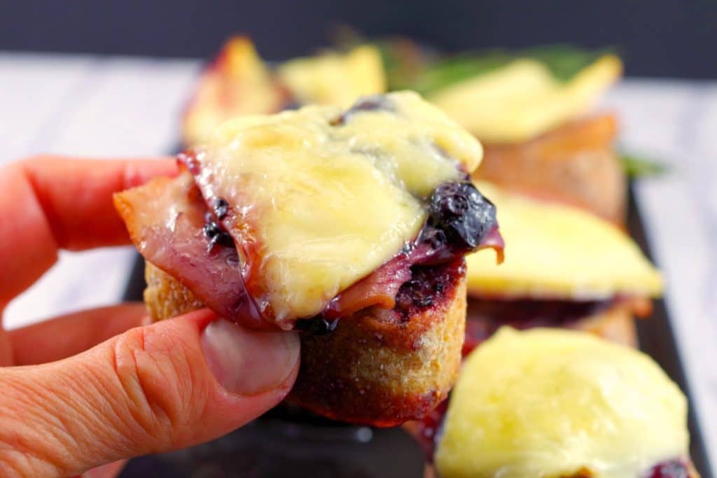 Brie turkey crostini in a hand, leftover turkey recipes