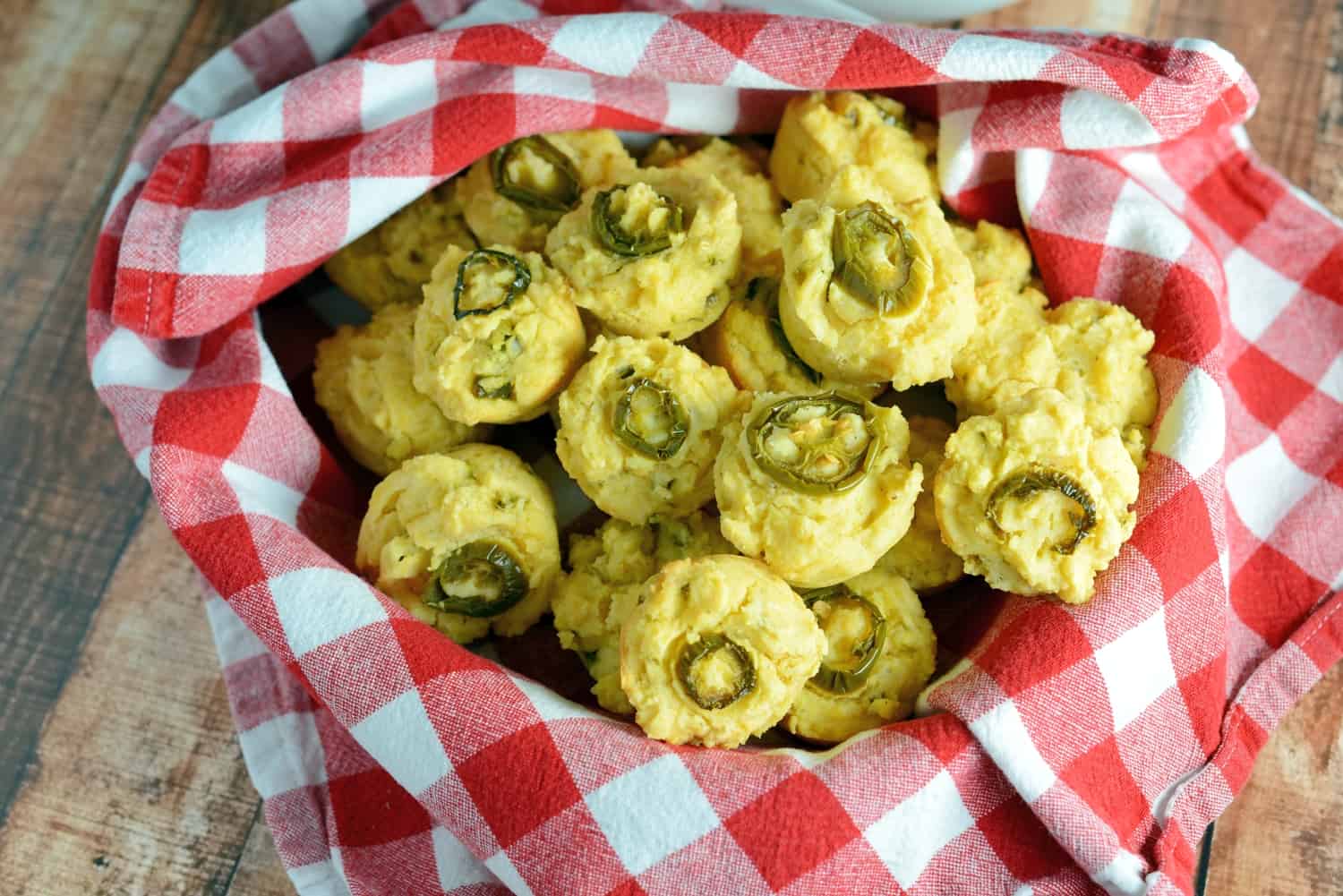 Thanksgiving sides jalapeno cornbread muffins in a basket with a checkered napkin