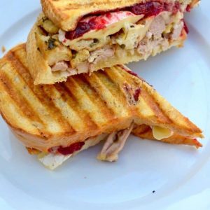 Thanksgiving panini cut in half on a white plate - leftover turkey recipes