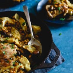 Chicken artichoke and olives in a skillet with a spoon - skillet dinners