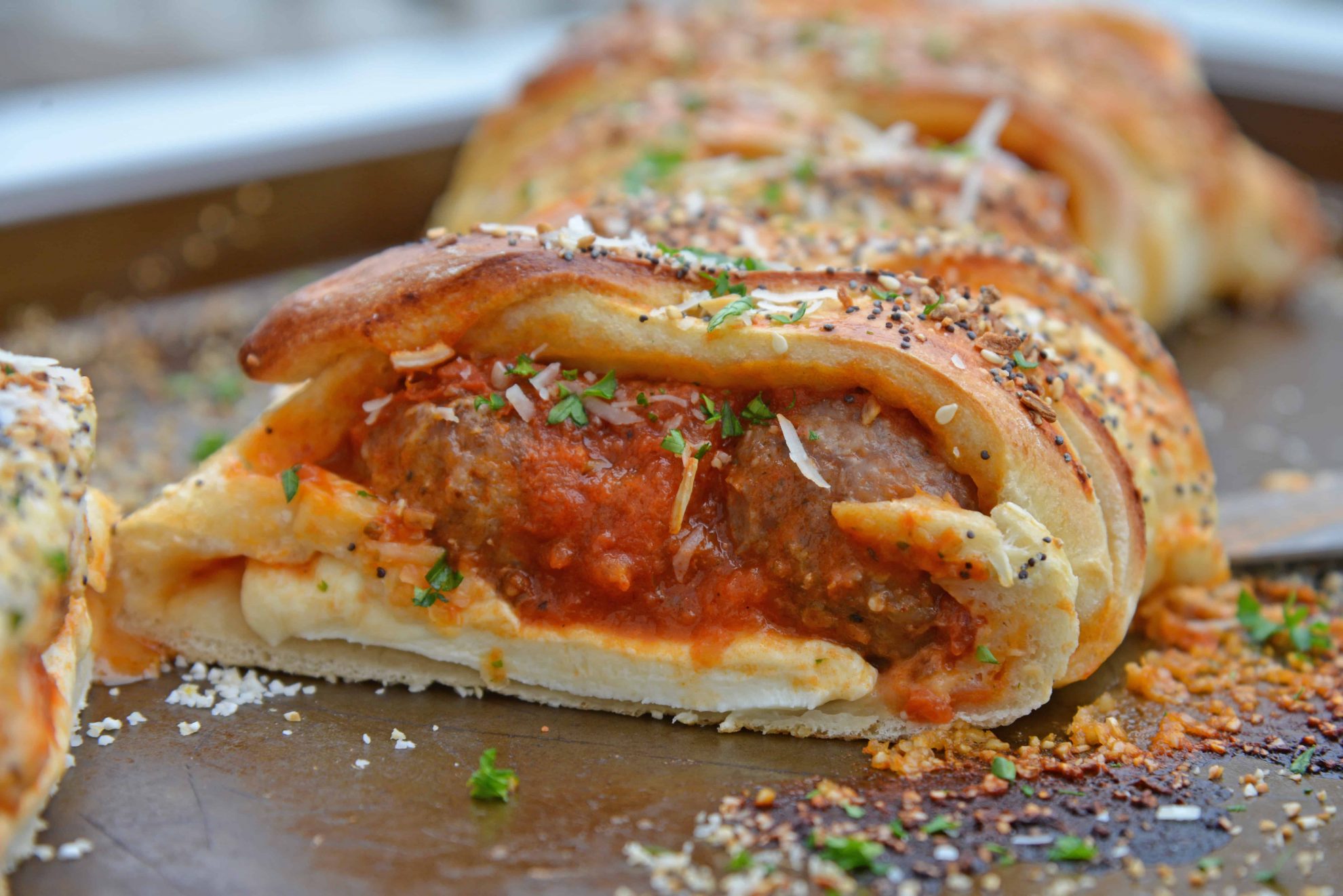 Everything Meatball Stromboli is meatballs, marinara sauce and cheese wrapped in pizza dough topped with everything bagel seasoning. An easy weeknight meal recipe! #howtomakestromboli #strombolirecipe #meatballstromboli www.savoryexperiments.com 