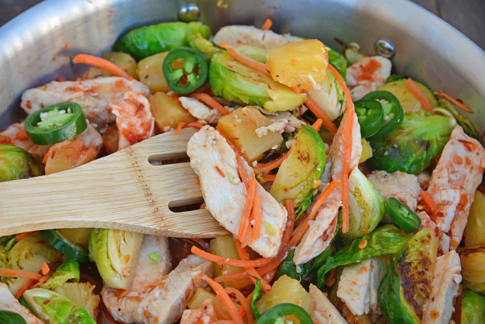 Quick Szechuan Chicken and Rice is an easy dinner recipe featuring chicken strips, brussels sprouts, carrots and pineapple over brown rice. All ready in 15 minutes! #quickchickendinners #szechuanchicken www.savoryexperiments.com 