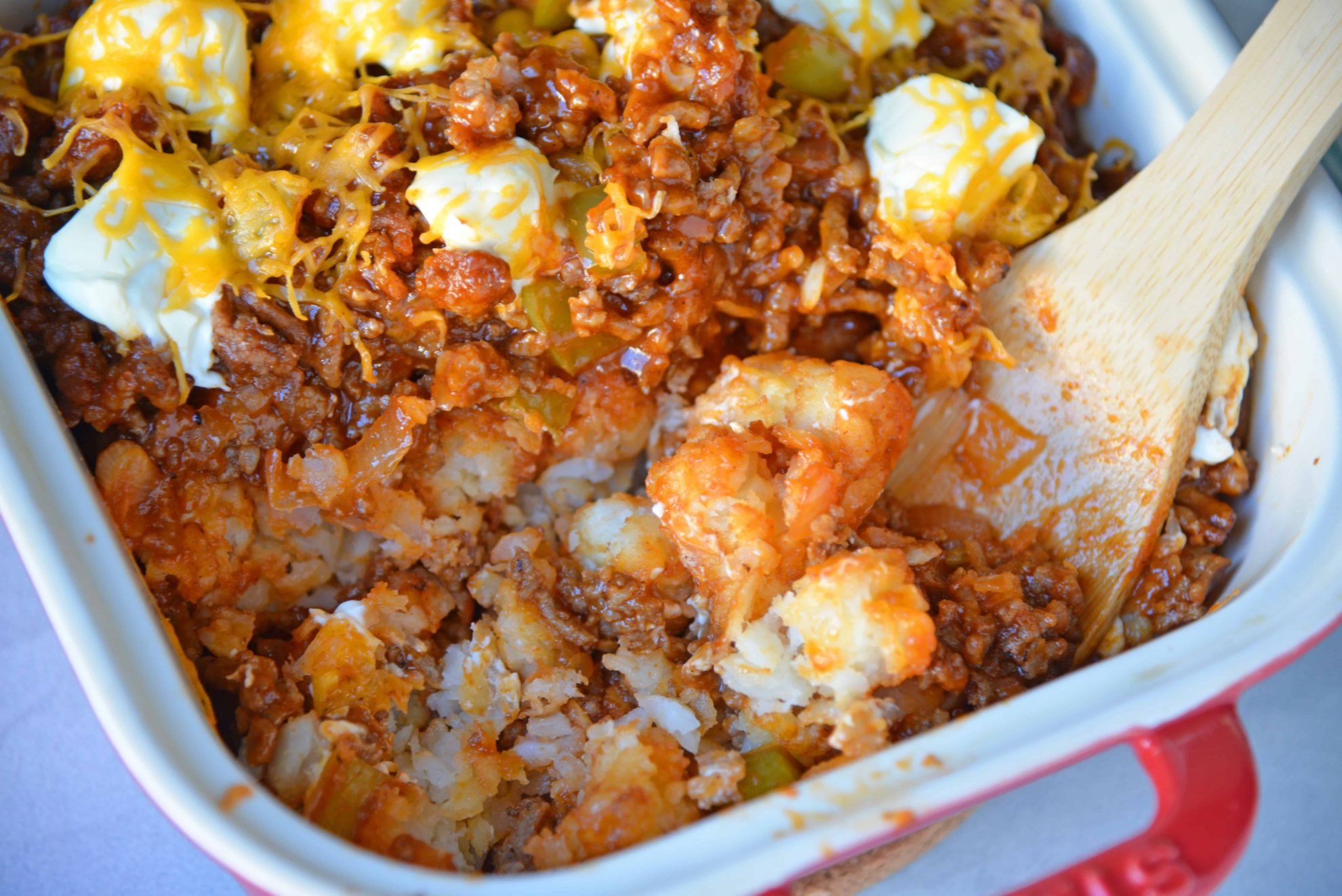 Sloppy Joe Tater Tot Casserole combines layers of crispy tater tots with homemade sloppy Joe mix, cream cheese and cheddar for the ultimate quick meal or party food! #tatertotcasserole #sloppyjoes www.savoryexperiments.com 