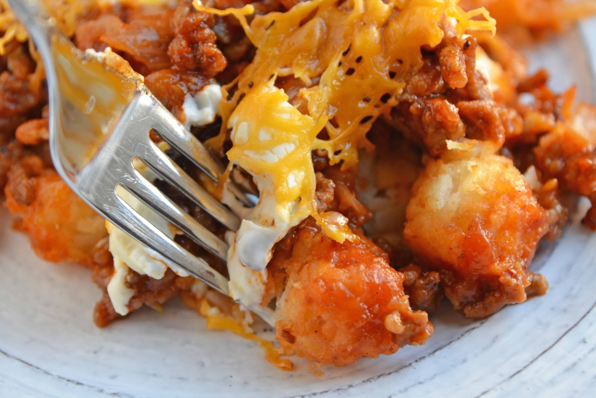 Sloppy Joe Tater Tot Casserole combines layers of crispy tater tots with homemade sloppy Joe mix, cream cheese and cheddar for the ultimate quick meal or party food! #tatertotcasserole #sloppyjoes www.savoryexperiments.com