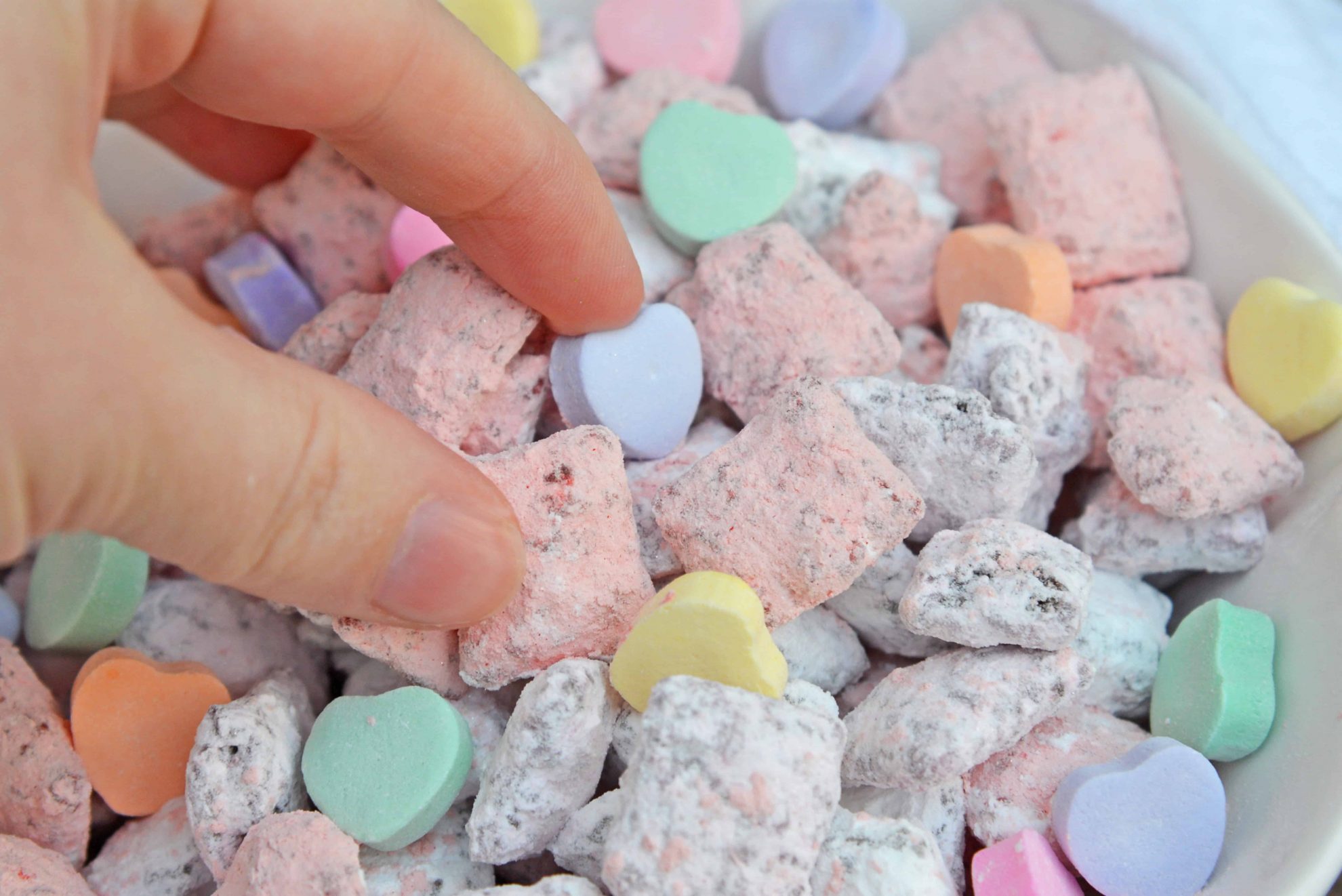 Valentine's Day Puppy Chow transforms a traditional muddy buddy recipe into a festive Cupid Crunch mix! The perfect no-bake dessert for any Valentine's Day party. #puppychow #valentinesdaydesserts #muddybuddy #nobakedesserts www.savoryexperiments.com