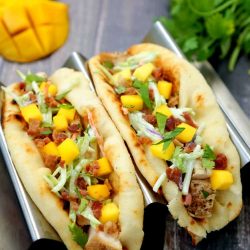 angled shot of two chicken bacon mango tacos