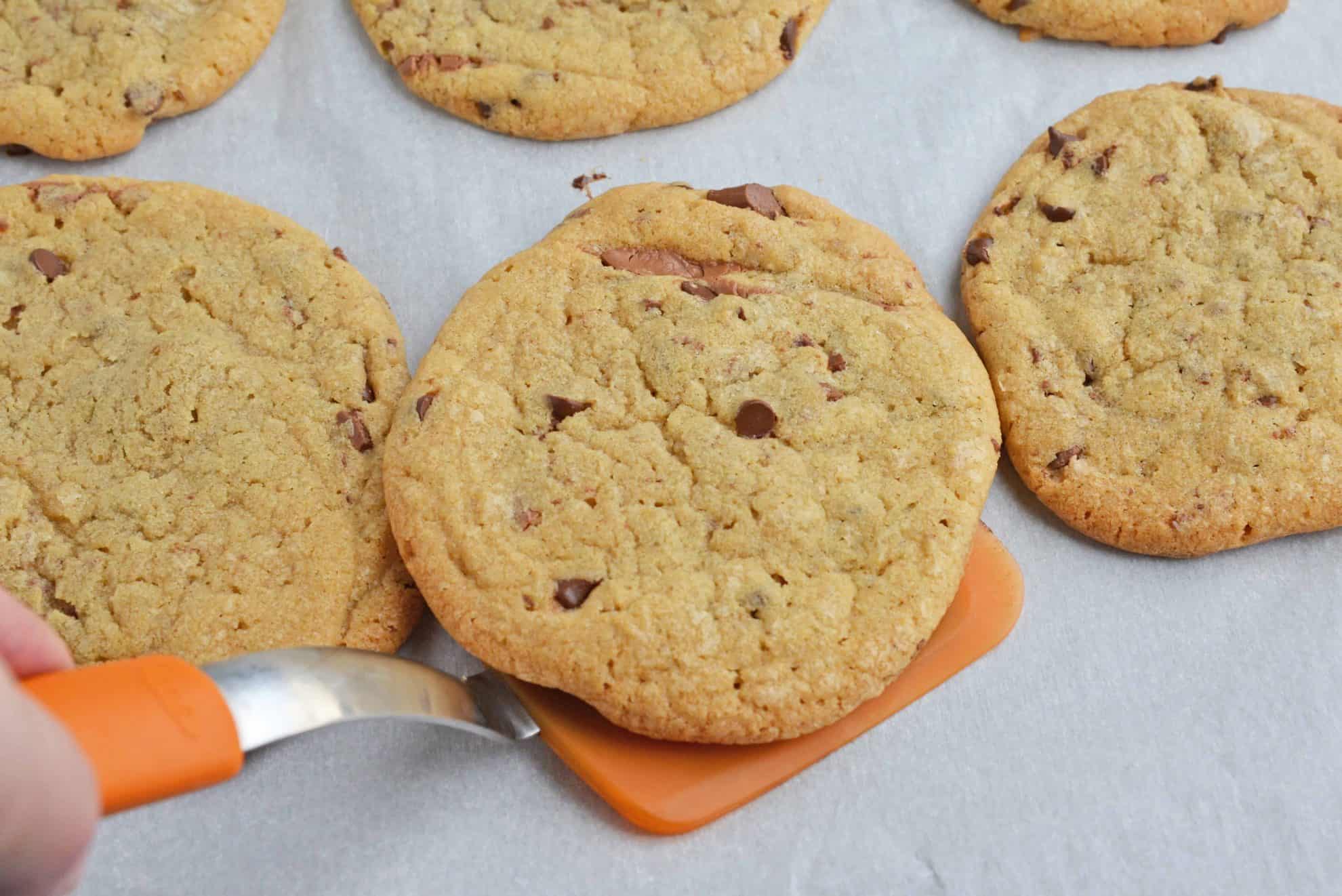 Chocolate chip cookie being scooped by a spatula 
