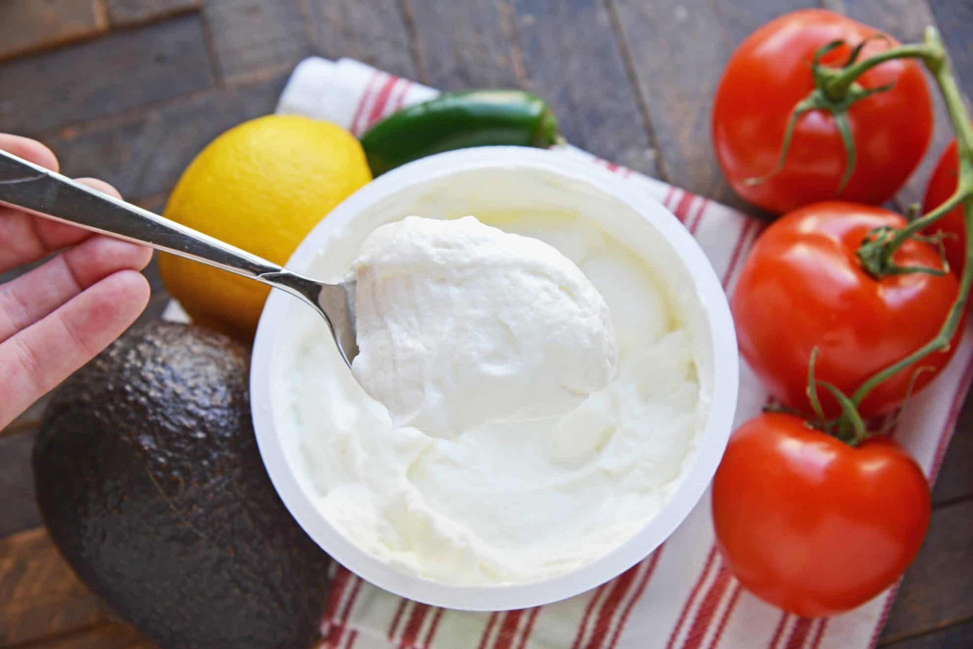 Spoonful of plain yogurt surrounded by fresh vegetables