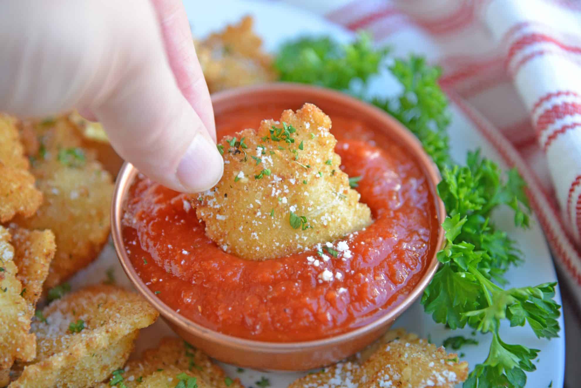 Fried ravioli dipping into marinara sauce