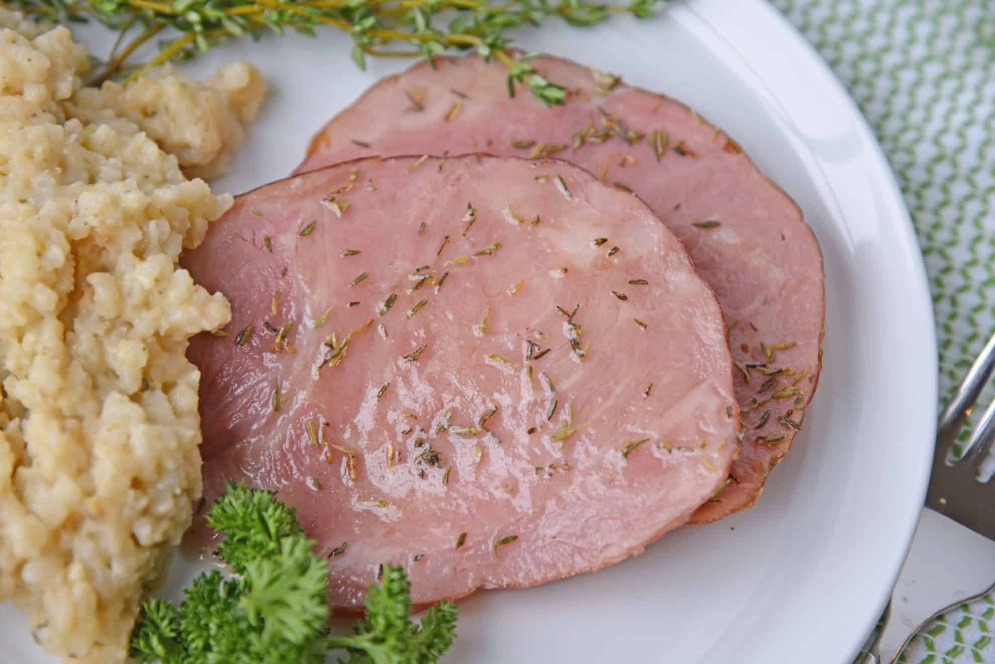 Two slices of glazed ham on a white plate