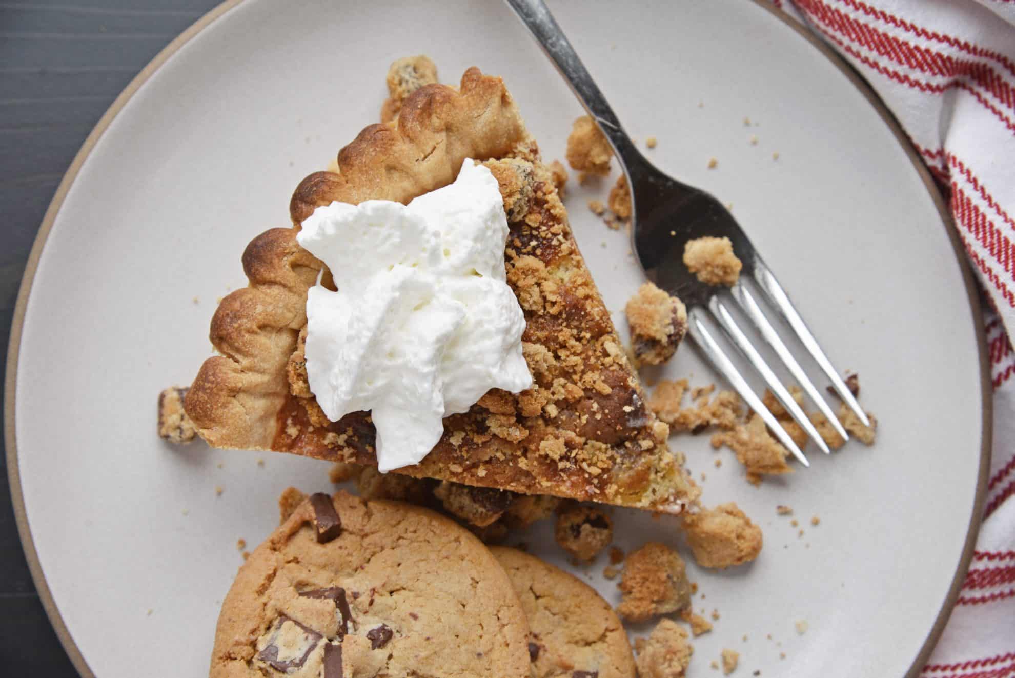 Overhead shot of slice of Chocolate Chip Pie on a white plate with cookie crumbles