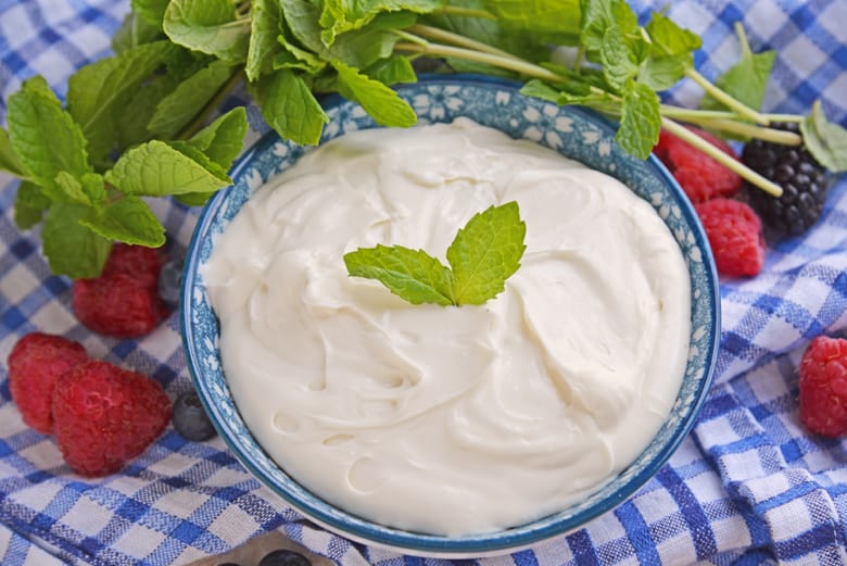 Angle of cream cheese fruit dip in a blue bowl with mint