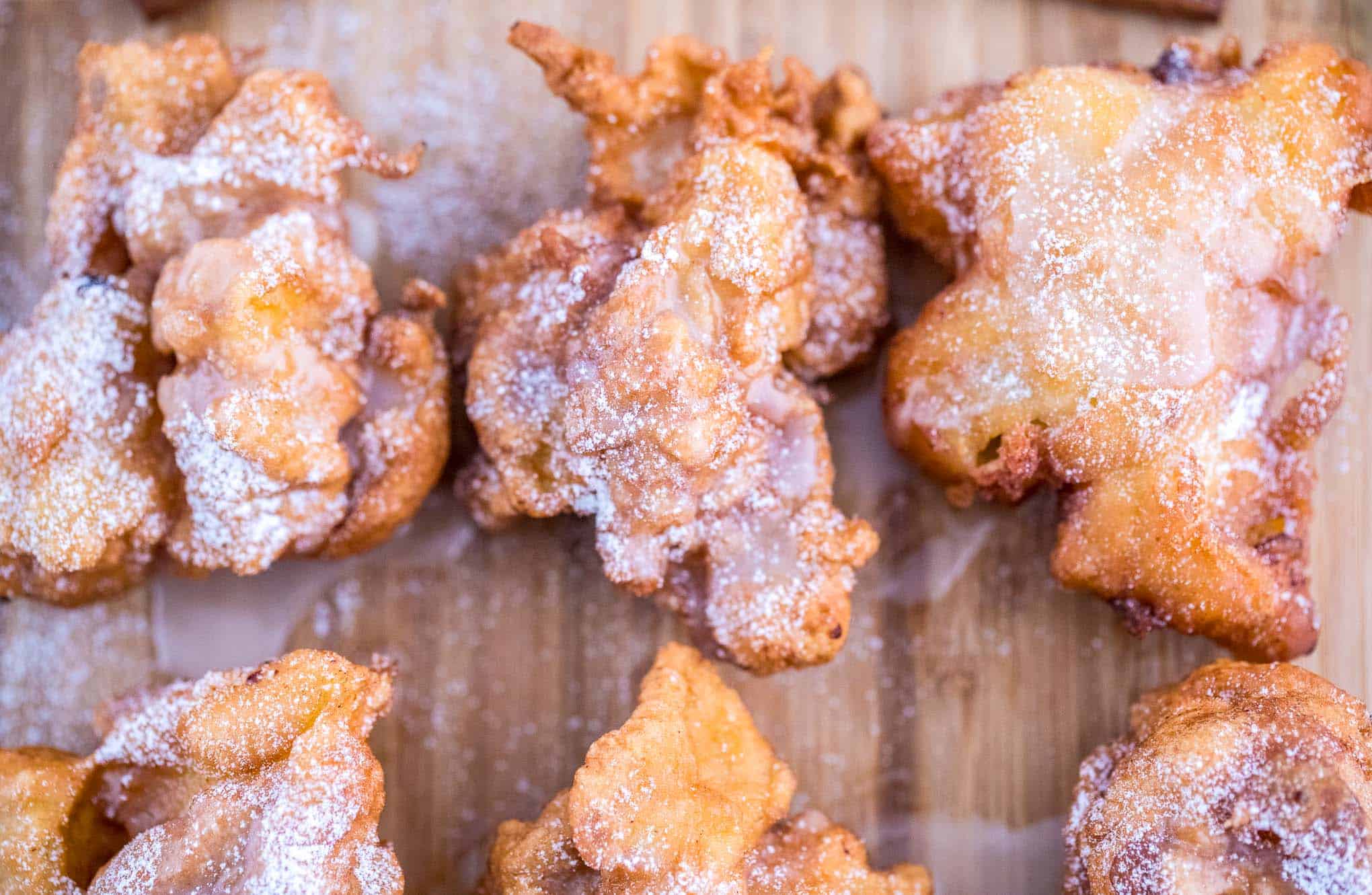 Drizzled apple fritters on a wood cutting board