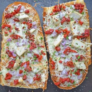 Two french bread pizzas on a baking sheet