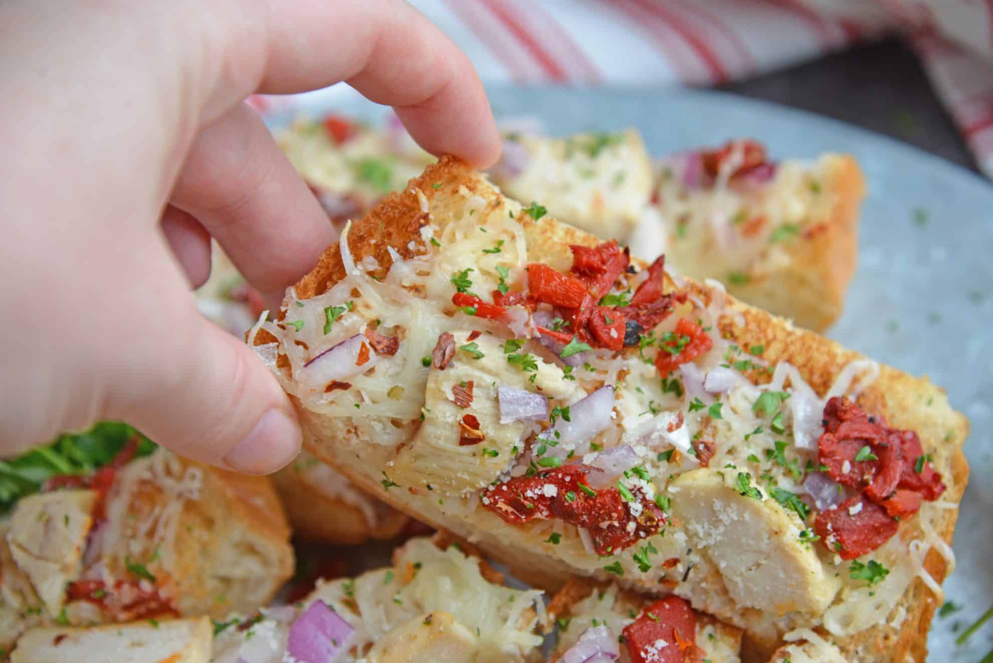 hand reaching in for a slice of french bread pizza