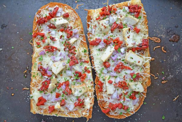 Two french bread pizzas on a baking sheet