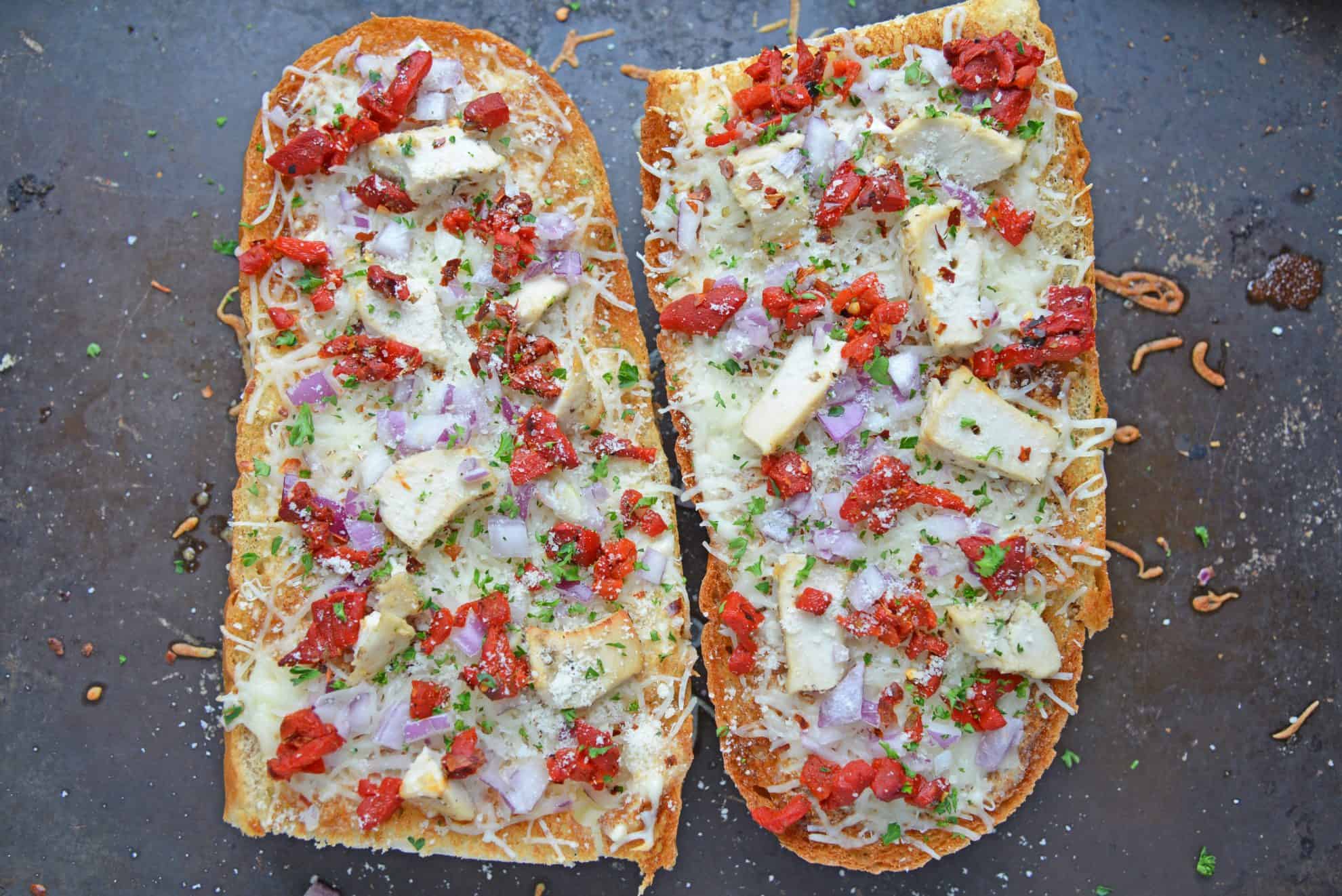 Two french bread pizzas on a baking sheet