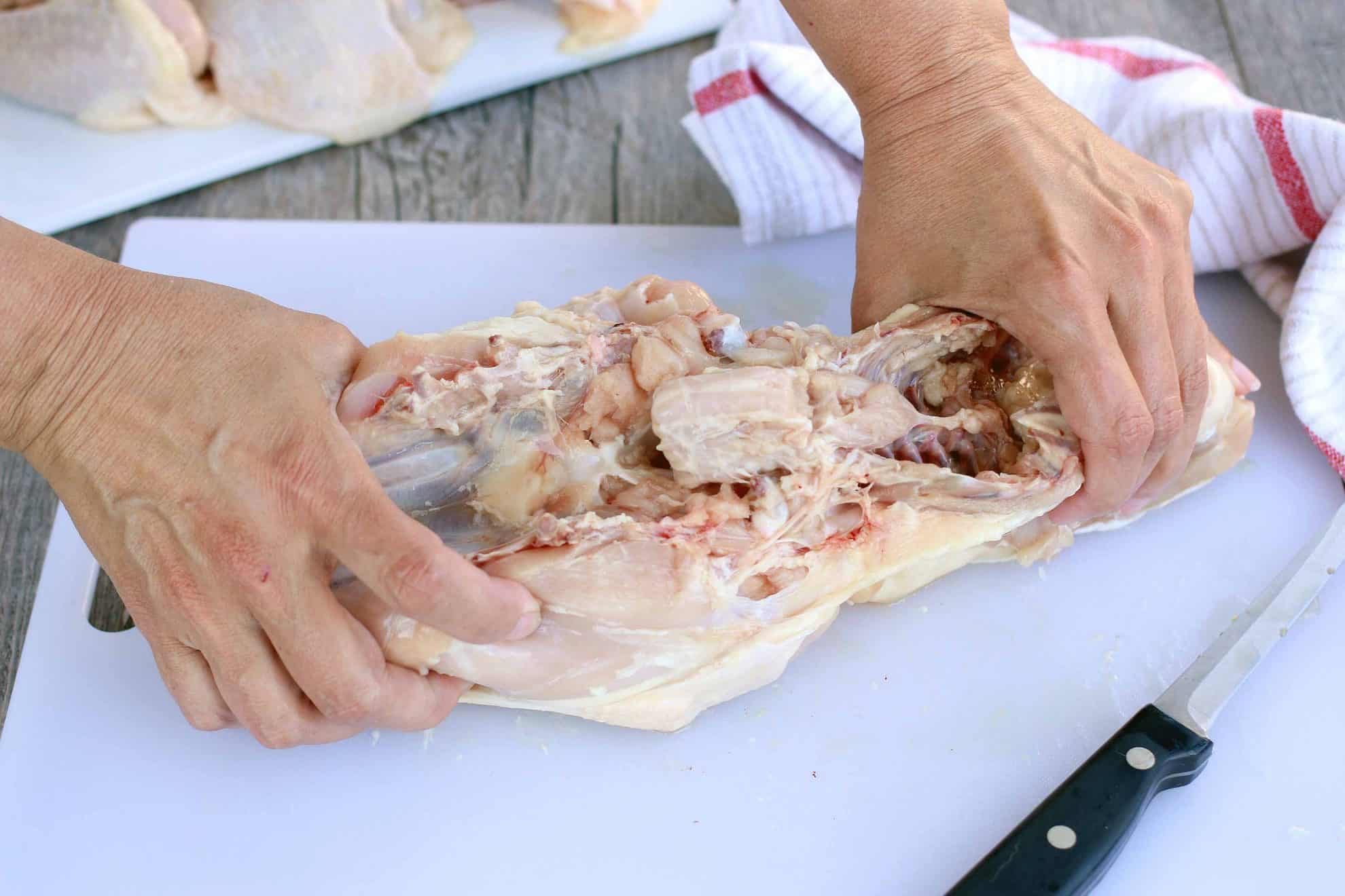 Removing the backbone of a chicken from the breast.