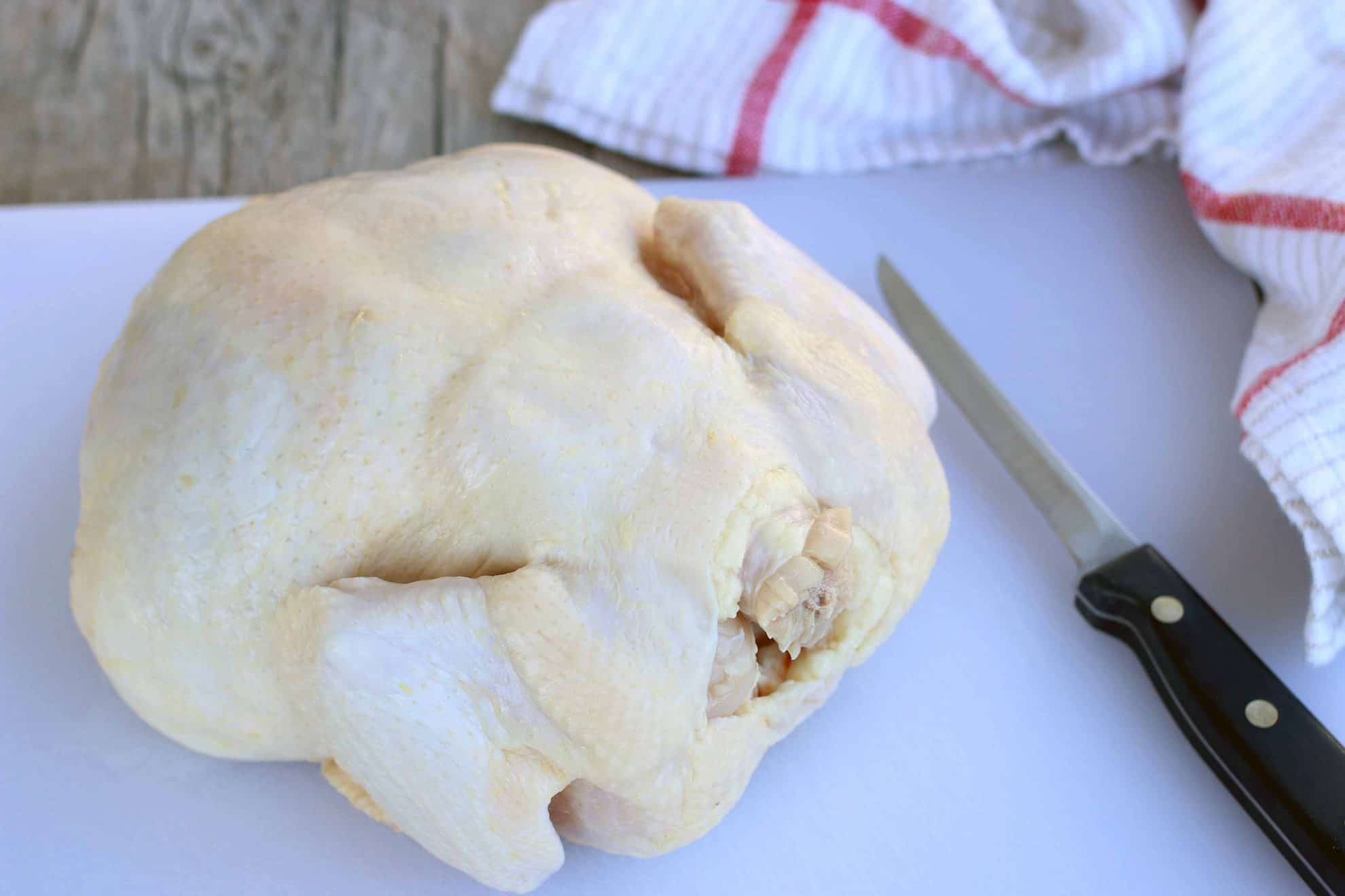 A whole chicken sitting on a cutting board.