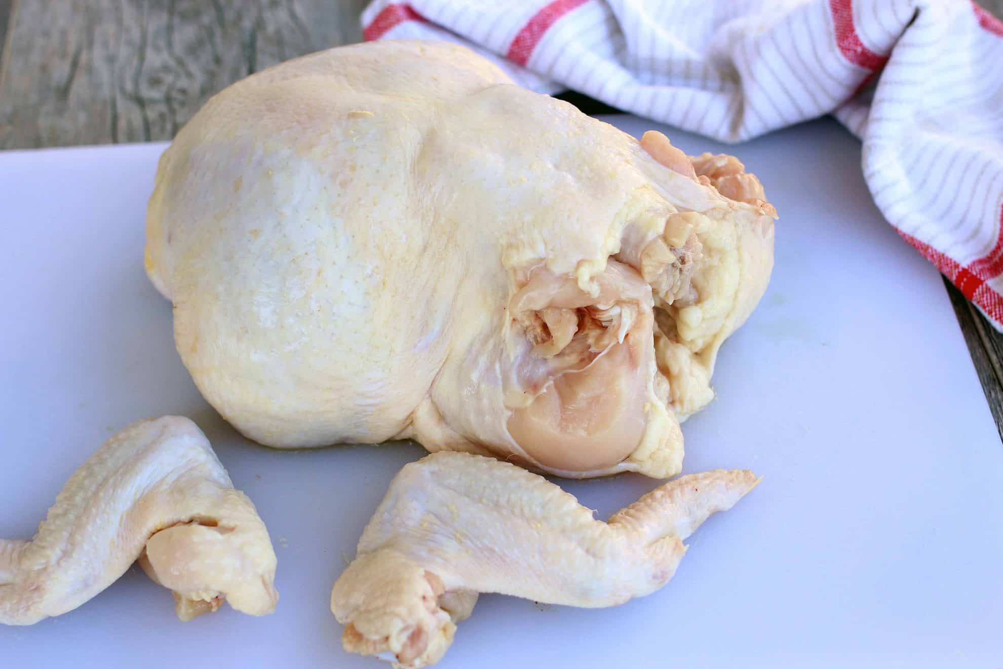 Cutting the legs and thighs from a whole chicken.